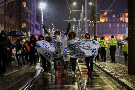 La gente espera bajo la lluvia antes de las celebraciones de Nochevieja en Edimburgo.