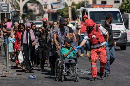 Un trabajador de la Media Luna Roja ayuda a los residentes, incluido un hombre en silla de ruedas, a evacuar el campo de refugiados de Jenin.
