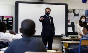 El presidente francés, Emmanuel Macron, usa una máscara protectora con una cinta azul-blanca-roja durante sus gestos durante una entrevista con escolares durante una visita a la escuela primaria Pierre de Ronsard en Poissy, Francia.