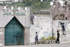 Los detenidos son observados por un guardia, segundo, desde la derecha, mientras se esfuerzan por quitar un mural de la pared de la prisión de Suva en la capital de Fiji.