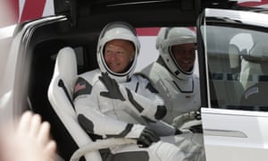 Los astronautas de la NASA Douglas Hurley, a la izquierda, y Robert Behnken se saludan sentados en un SUV Tesla en ruta hacia el Pad 39-A en el Centro Espacial Kennedy en Cabo Cañaveral.
