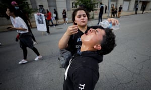 Un manifestante vierte agua en los ojos de un amigo que sufre gases lacrimógenos durante una manifestación en Raleigh, Carolina del Norte.