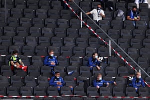 Miembros del equipo SC Paderborn con máscaras protectoras mientras observan desde las gradas.