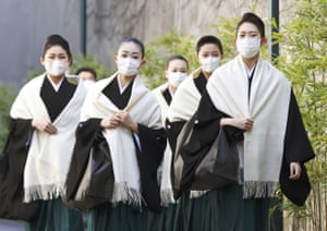 Los estudiantes de la Escuela de Música de Takarazuka usan máscaras mientras caminan hacia su ceremonia de graduación en Takarazuka, en el oeste de Japón, el 2 de marzo, en medio de la propagación del coronavirus.