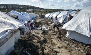 Los refugiados cavan trincheras para evitar que el agua entre en sus tiendas en el campamento temporal de Lesbos.