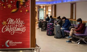 Los miembros del público en el aeropuerto de Manchester esperan junto a un cartel que desea a los pasajeros una Feliz Navidad