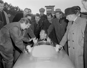 Stirling Moss se sienta en la cabina de un auto de gran premio Mercedes-Benz que acaba de probar.