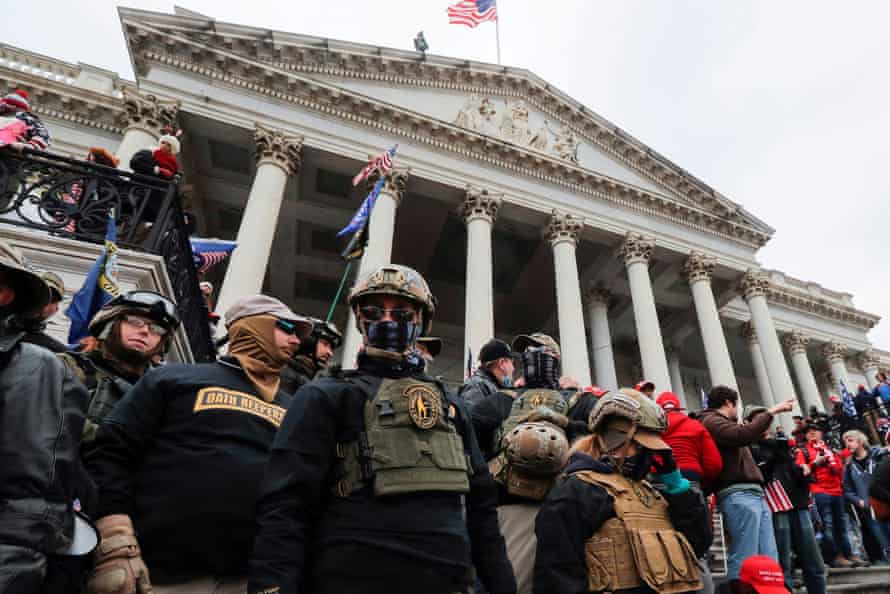 Un grupo de personas en uniforme militar se paran en los escalones frente al Capitolio de los Estados Unidos.
