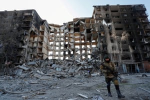 Un militar de las tropas prorrusas camina cerca de un edificio destruido en la ciudad portuaria sitiada de Mariupol, Ucrania.