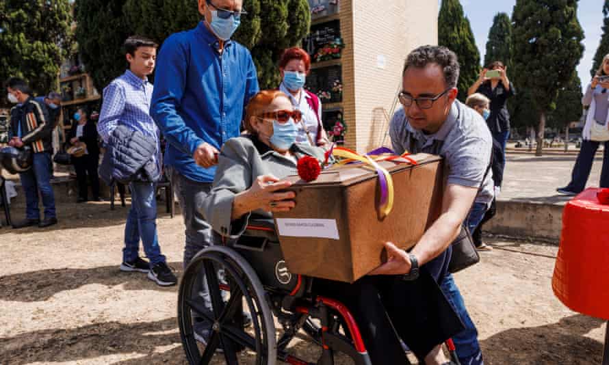 Una persona en silla de ruedas recibe una caja que contiene los restos humanos