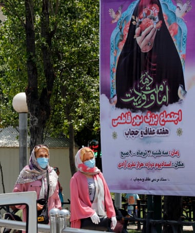 Mujeres iraníes pasan frente a una valla publicitaria sobre el nuevo código de vestimenta en Teherán el 12 de julio.  La policía iraní ha comenzado a advertir a las mujeres sobre su ropa y peinados en muchas ciudades de Irán.