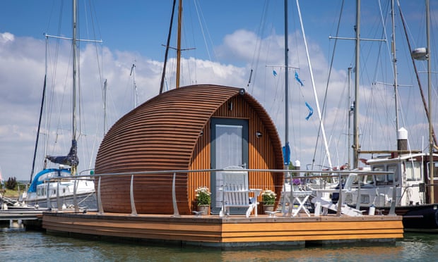 Una pequeña cabaña de madera inspirada en un arco sobre una plataforma flotante