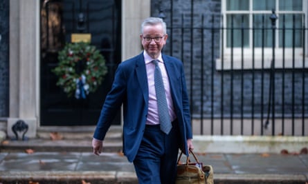 Michael Gove saliendo de Downing Street, sonriendo, con una cartera de cuero marrón.
